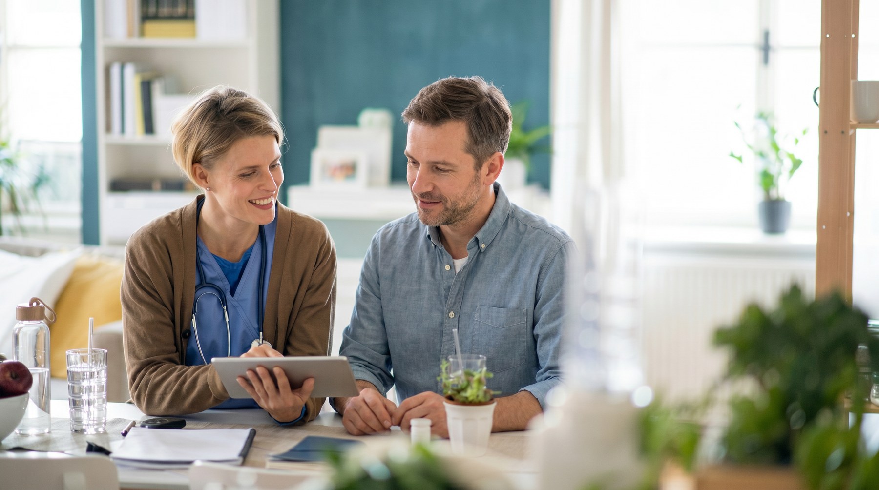 Quantify nurse reviewing a care plan on a tablet with her patient at home, warm kitchen setting
